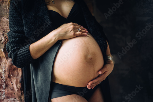 pregnant woman hugging belly in underclothes lace stockings hugging photo