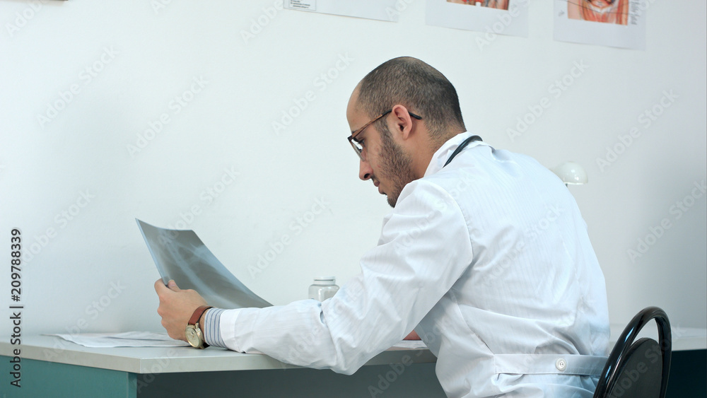 Young male doctor examining chest xray image Young male doctor examining chest xray image