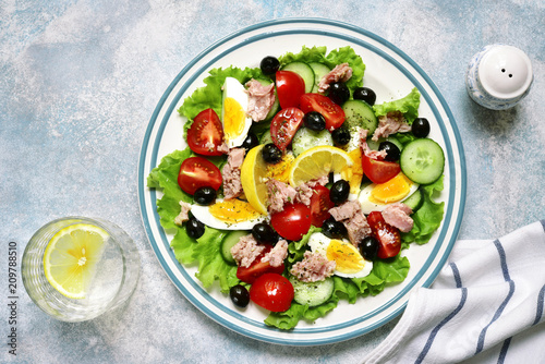 Tuna salad with cherry tomatoes, cucumber, black olives and boiled eggs.Top view.