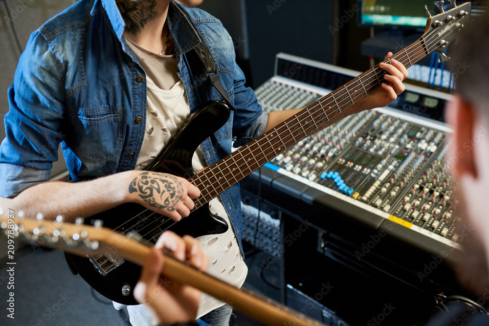 Fototapeta premium Crop shot of modern performers playing guitars in sound studio while collaborating new song. 