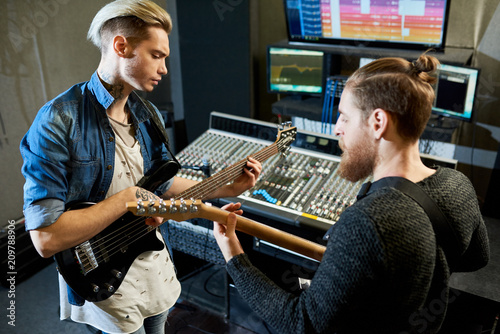 Photography Two men with guitars playing together while making new song and recording it in sound studio