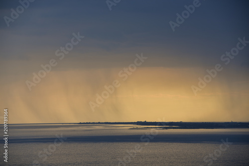 Thunderstorm over coast and the Mediterranean sea at sunset with rain showers. Golden hour. 