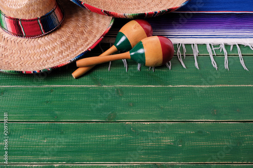 Mexico cinco de mayo fiesta carnival traditional green wood background border mexican sombrero maracas and serape rug or blanket photo