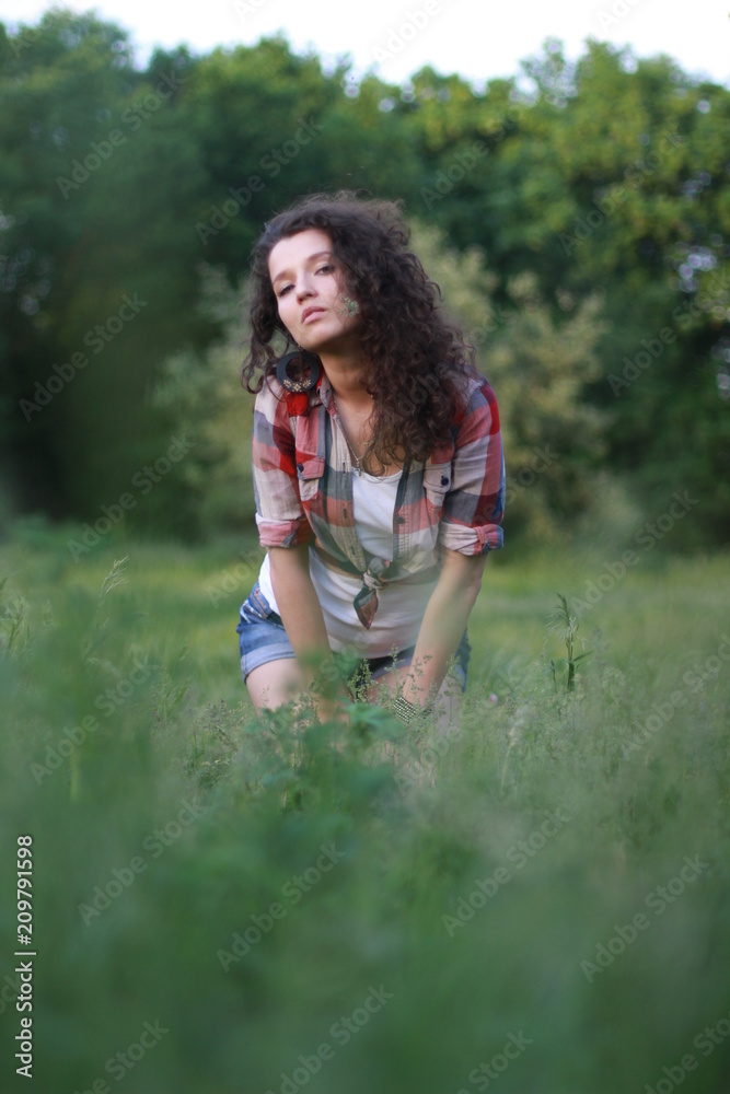 Young, beautiful woman on nature. Young woman with dark curly hair.