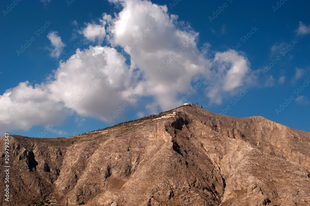Desert mountain with white buildings on a top, clear blue sky background. Picturesque view of Santorin, Greece, Europe. Traveling concept background. Cycladic island.