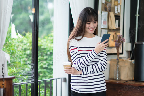 Free Download Asian woman talking on mobile phone video call and standing at cafe restaurant near window see through garden,Digital age lifestyle,Working outside office concept. - GFXLoad
