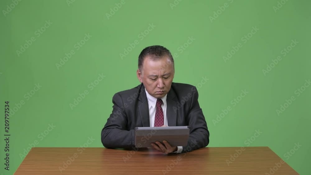 Mature Japanese businessman working with digital tablet Mature Japanese businessman working with digital tablet