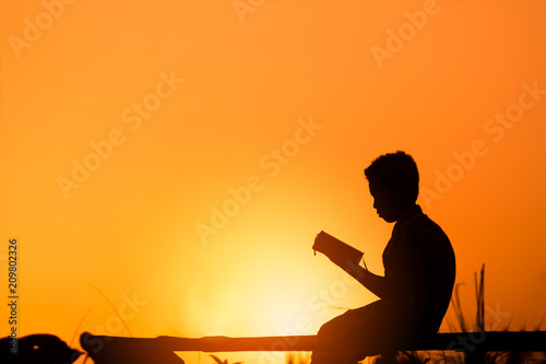 Boy reading holy bible on wood , christian silhouette concept.