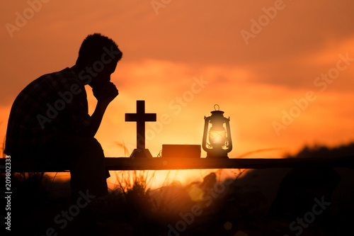 boy praying and reading holy bible on wood , christian silhouette concept.