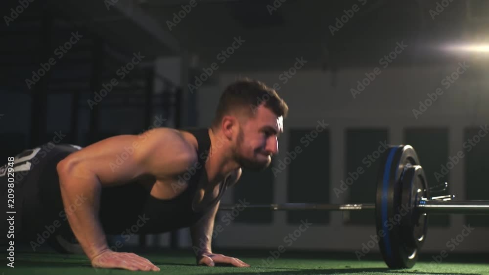 Nice guy with a beard prepares to make a pushup in the gym on the black background Nice guy with a beard prepares to make a pushup in the gym on the black background