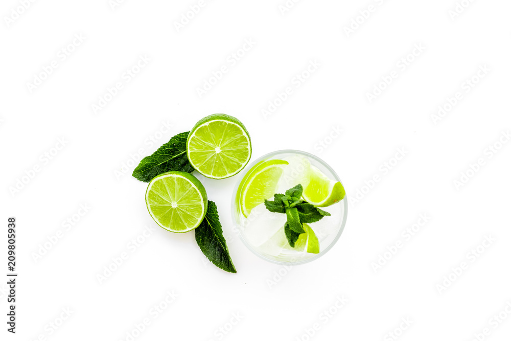 Refreshing mojito cocktail. Slices of lime, mint, glass with ice cubes on white background top view space for text Refreshing mojito cocktail. Slices of lime, mint, glass with ice cubes on white background top view space for text