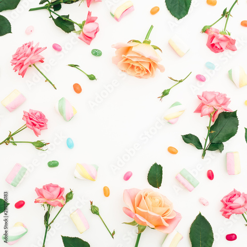 Frame pattern with roses flowers  buds  leaves and marshmallows with candy on white background. Flat lay  top view.