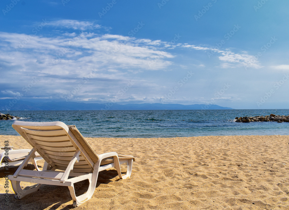 Beach, city and ocean view in Puerto Vallarta Mexico with beach chairs and coastline.