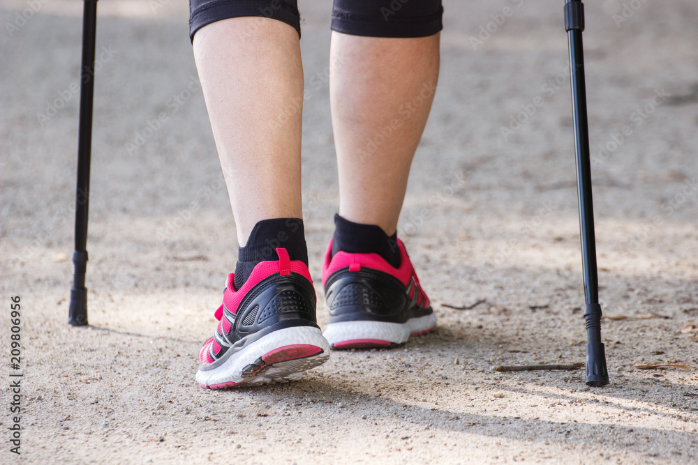 Legs of elderly senior woman practicing nordic walking, sporty lifestyles in old age concept Legs of elderly senior woman practicing nordic walking, sporty lifestyles in old age concept