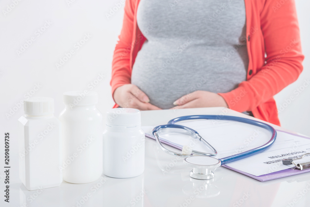 Medicine bottles with pregnant woman in background,Medication with pregnancy concept.