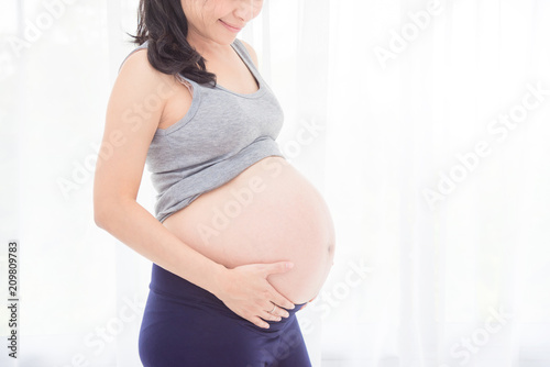 Cropped image of asian pregnant woman,holding her belly in front of bright window. Free Download Cropped image of asian pregnant woman,holding her belly in front of bright window. - GFXLoad