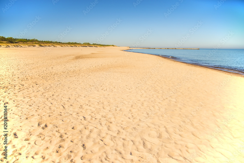 lonesome beach of the Baltic Sea with blue sky and sail boat