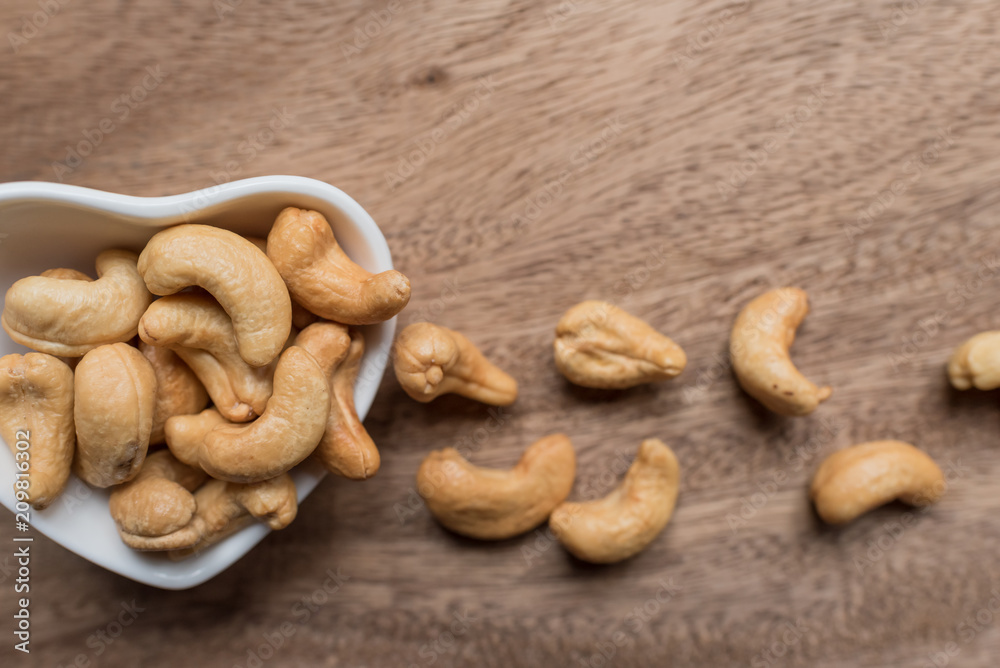 Raw cashew nuts in bowl on textured wooden background, table top view Raw cashew nuts in bowl on textured wooden background, table top view