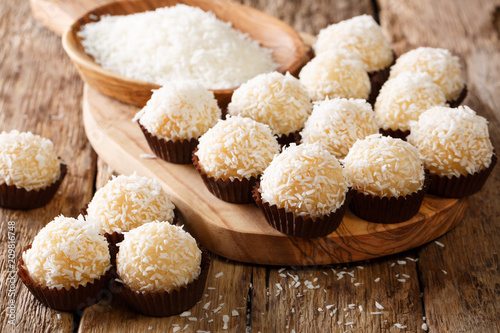 Appetizing candy balls beijinhos de coco with condensed milk and coconut close-up. horizontal