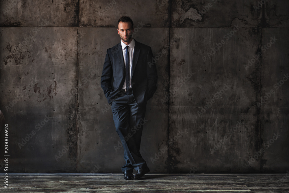 Obraz premium handsome man wearing black suit on a grunge background.