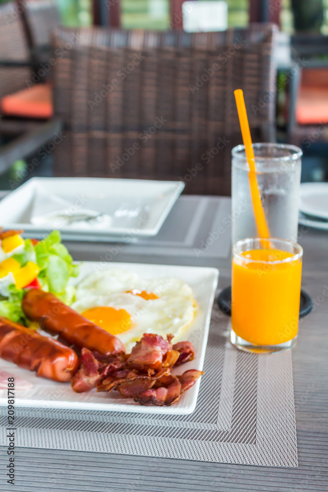 American Breakfast is foods with health benefits on table./ Bread basket, orange juice, fried egg, sausage, ham, salad, fried bacon are foods with health benefits in morning. American Breakfast is foods with health benefits on table./ Bread basket, orange juice, fried egg, sausage, ham, salad, fried bacon are foods with health benefits in morning.