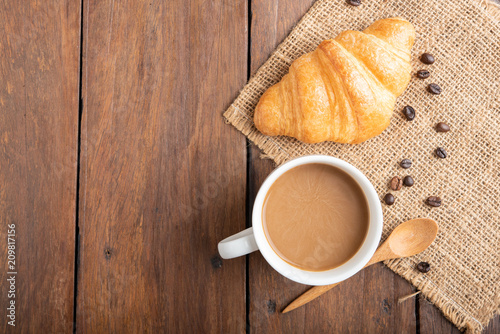 Coffee and croissant on wooden background
