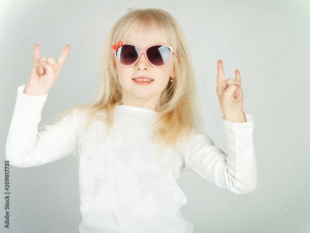 little girl in a fashionable blouse and pink glasses, making her face and happy little girl in a fashionable blouse and pink glasses, making her face and happy