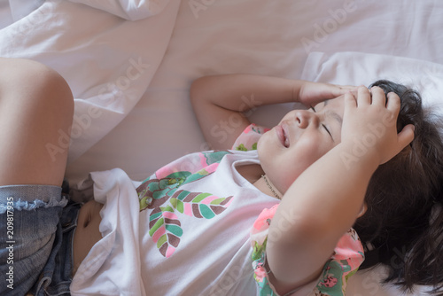 a little girl in her bed has a headache