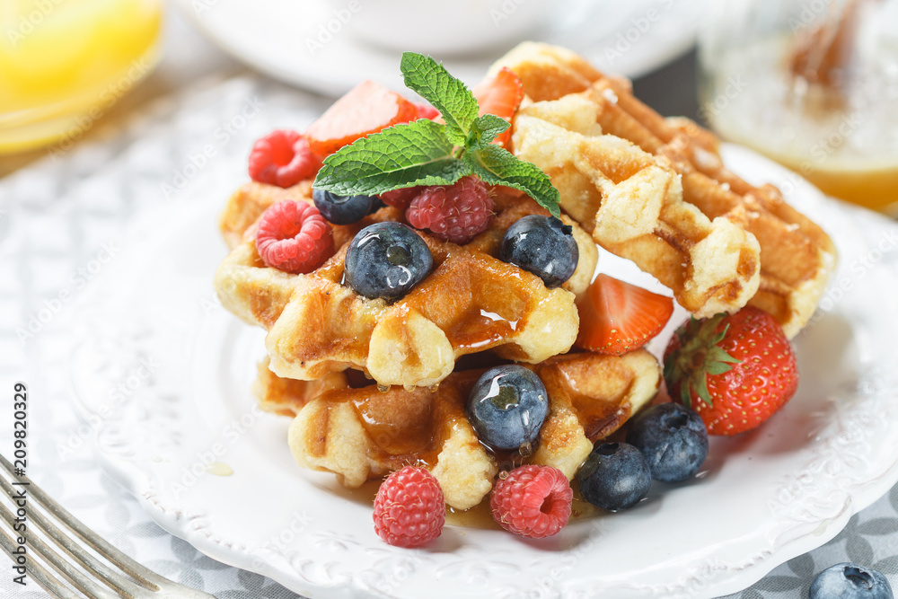 Fresh homemade waffles with raspberries, strawberries, blueberries and honey. Delicious Breakfast with berries