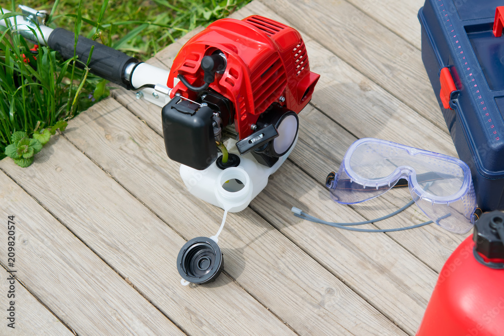 for refueling and servicing the mower, lie items in the drawer and safety glasses on a wooden background