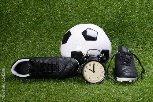 soccer ball, boots and alarm clock, on grass background