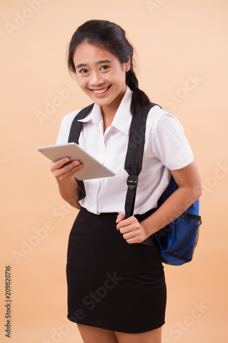 asian thai college woman student; education portrait of happy smiling college woman student carrying backpack, hand holding computer tablet; concept of college student education, university education
