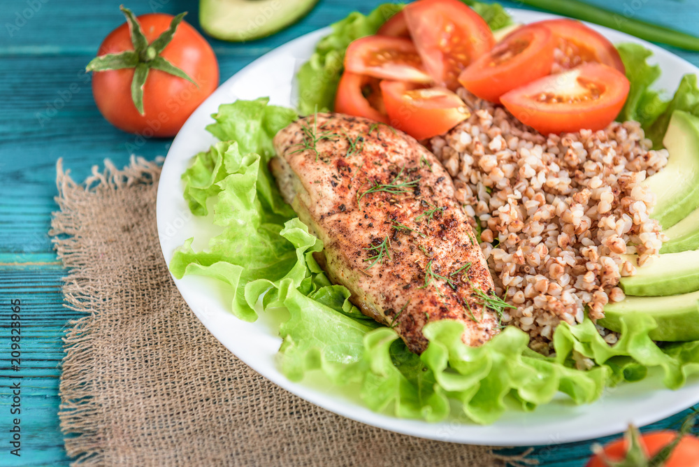 Grilled chicken breast with buckwheat porridge, tomatoes and avocado on blue wooden background. Diet nutrition, healthy food for lunch. Grilled chicken breast with buckwheat porridge, tomatoes and avocado on blue wooden background. Diet nutrition, healthy food for lunch.