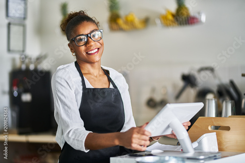 friendly shop assistant ready to take customer orders at register in restaurant photo