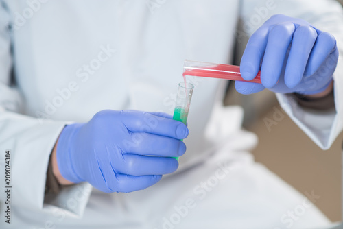 A young man scientist or doctor working with test tubes in lab