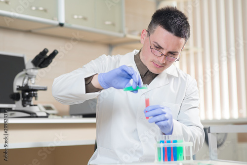 A young man scientist or doctor working with test tubes in lab