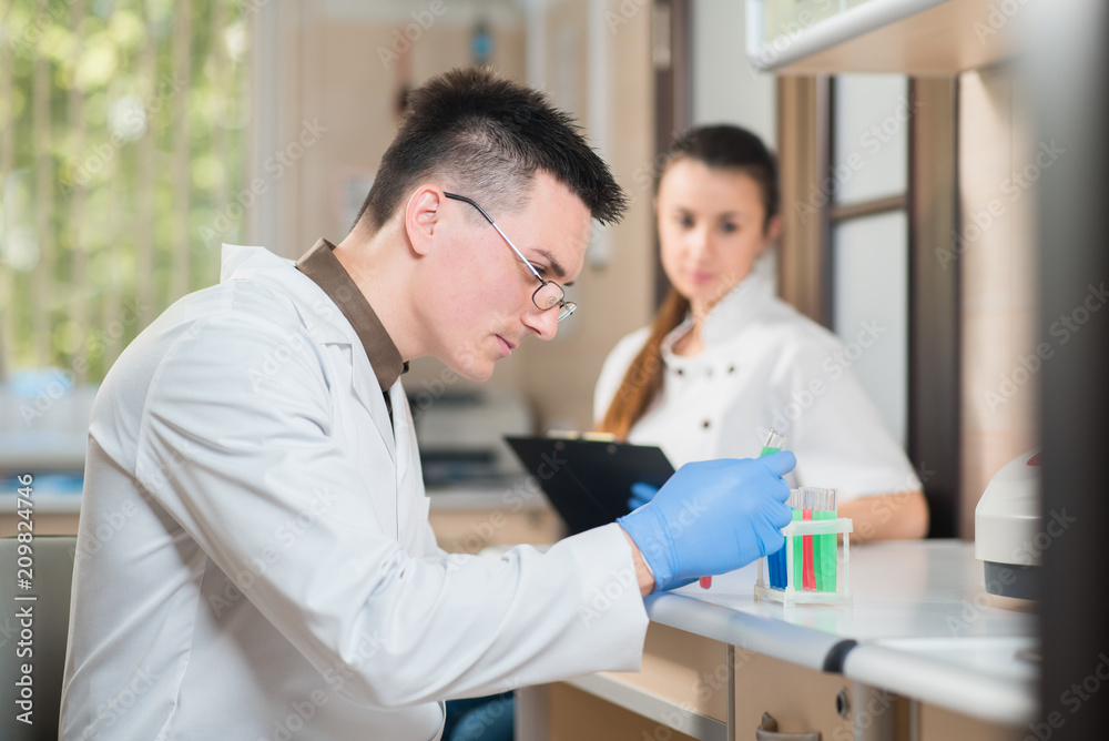 Young doctor or scientist working with assistant in lab Young doctor or scientist working with assistant in lab