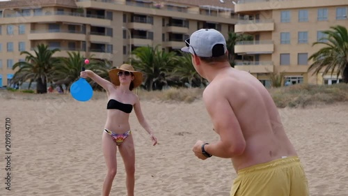 Young couple playing smash ball beach tennis