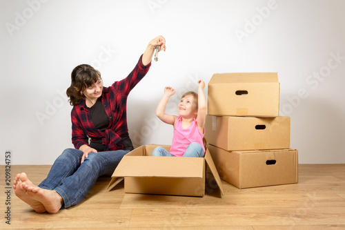 Mom and daughter put things out of the boxes after moving to a new house. The joy of buying new homes © penyushkin