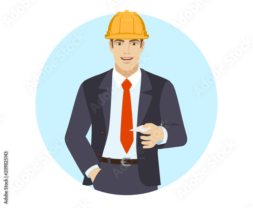 Businessman in construction helmet with hand in pocket gives a business card