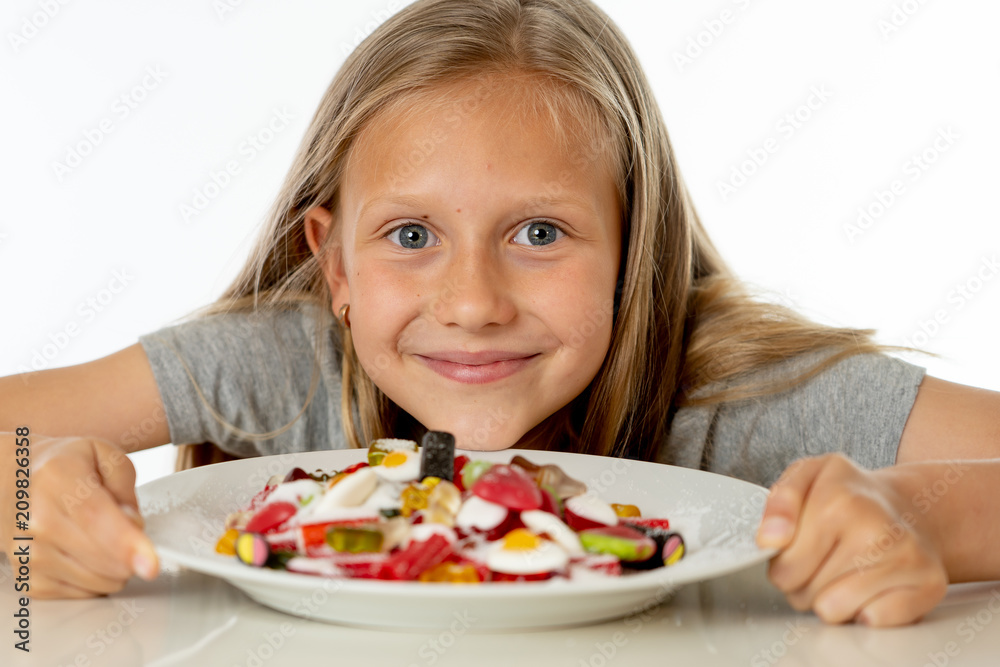 happy young girl holding a plate full of candy lollies on white background