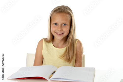 cute young girl studying at home on a desk with a study book on a white background