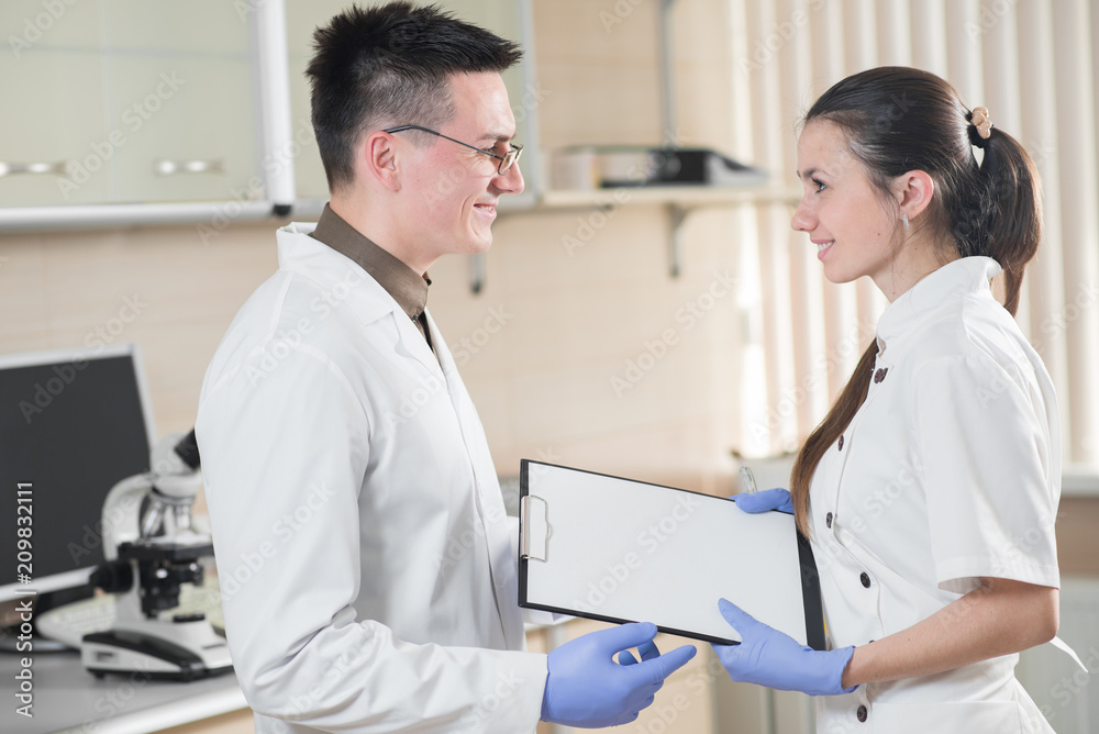 Obraz premium Young doctor or scientist with his assistant in lab. Team working