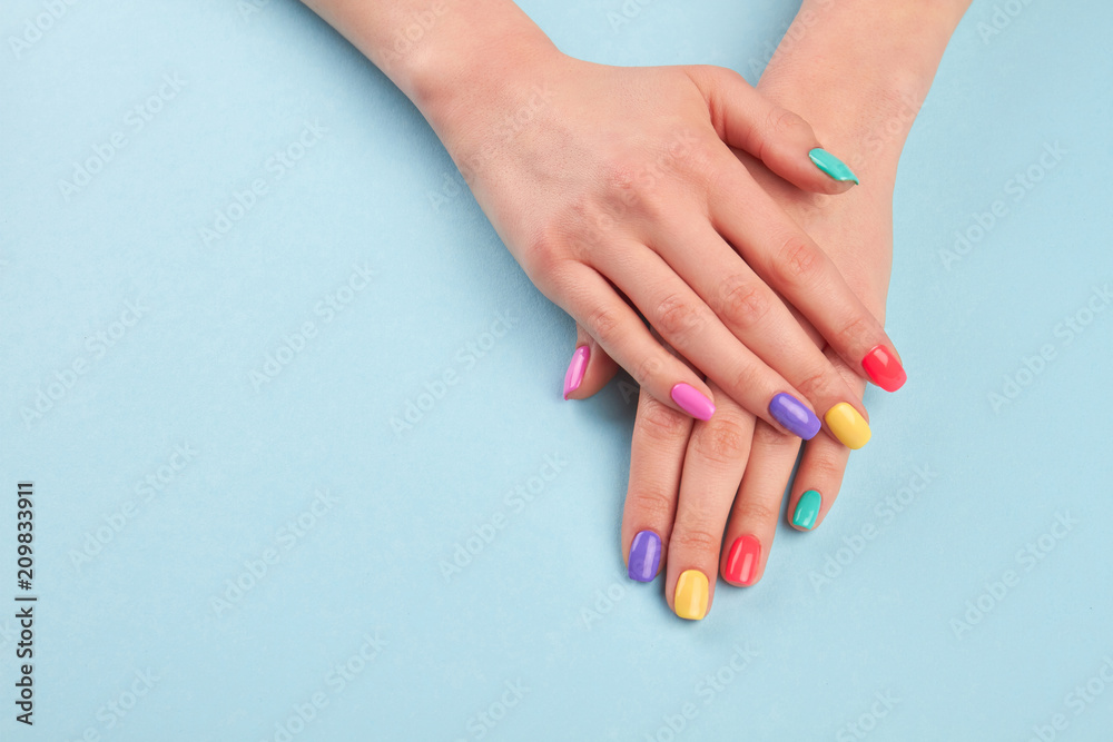 Hands with beautiful manicured nails. Girl hands with beautiful summer manicure on blue background in studio. Manicured hands and copy space. - obrazy, fototapety, plakaty 