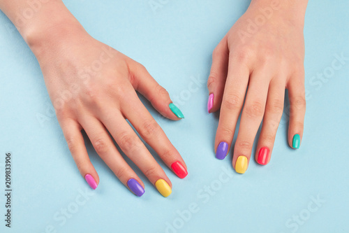 Female hands with beautiful summer manicure. Young woman hands with pastel colors nails on light blue salon table. Nail and skin treatment.