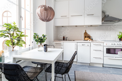 stylish kitchen with white cupboards grey tiled floor and stlish scandinvian furnitures photo