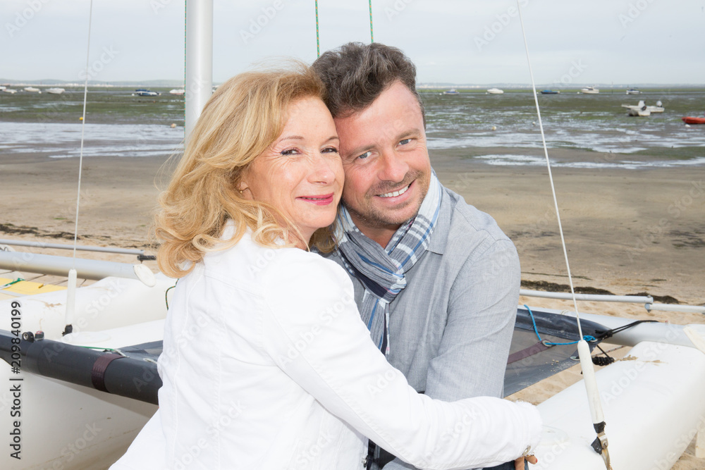 Senior couple embracing in front of beach with boat in vacation