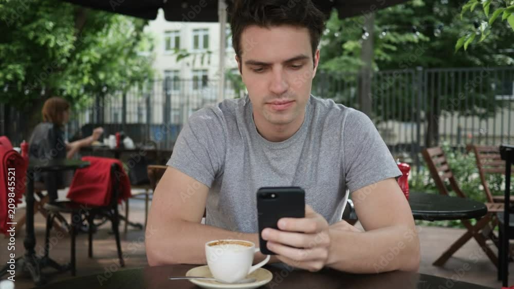 Man Using Smartphone while Sitting in Cafe Terrace