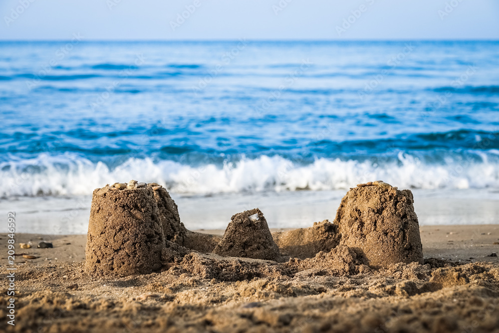 A sand castle on a beach with the sea and the horizon in the background. Crete, Greece. Concept for traveling with children / family, vacation and holiday.