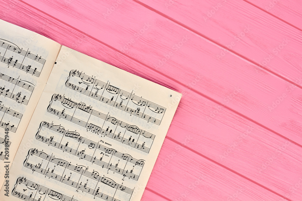Fototapeta premium Sheet with musical notes, copy space. Paper with music notes on pink wooden table.
